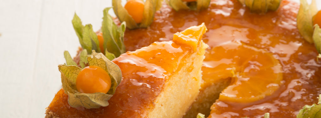 Orientalische Orangentorte mit glänzender Glasur und Physalis, ein Stück angeschnitten