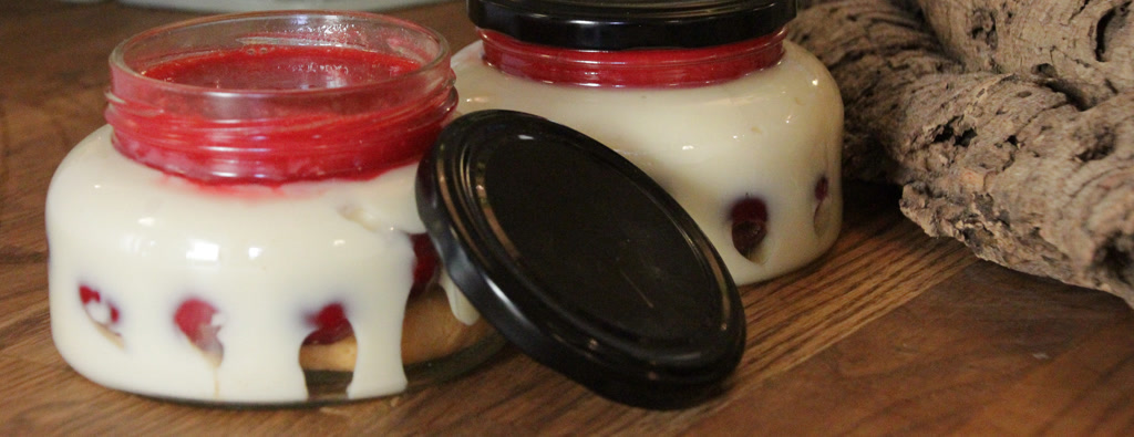 Zwei Torten im Glas mit roter Fruchtschicht auf einem Holztisch